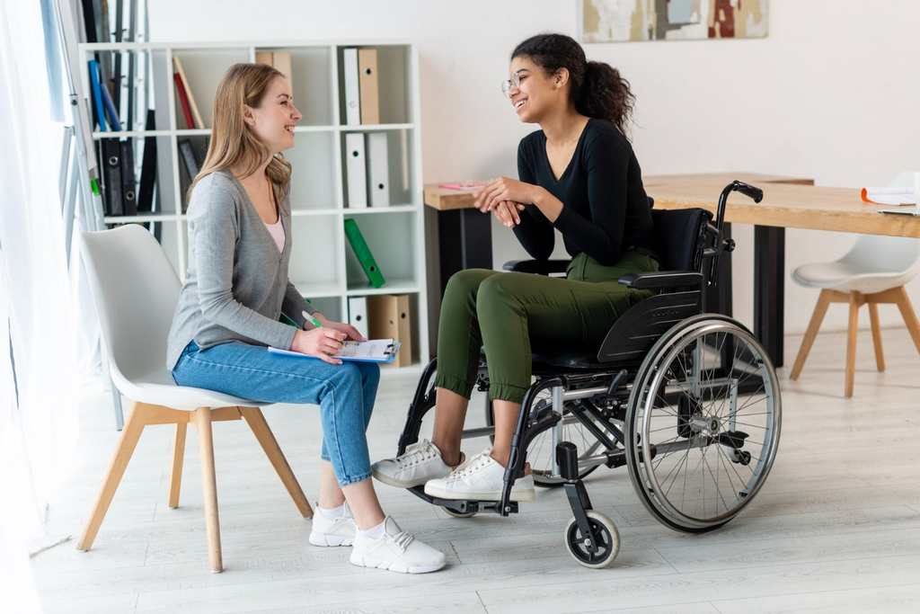 Illustration of two people talking in a community-centre foyer, one using a cane. Not a Villa participant or employee.